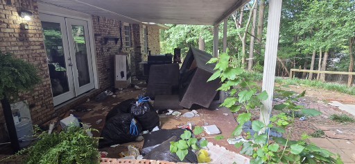 Heavy junk and debris on a covered back patio before cleanout in Columbus GA