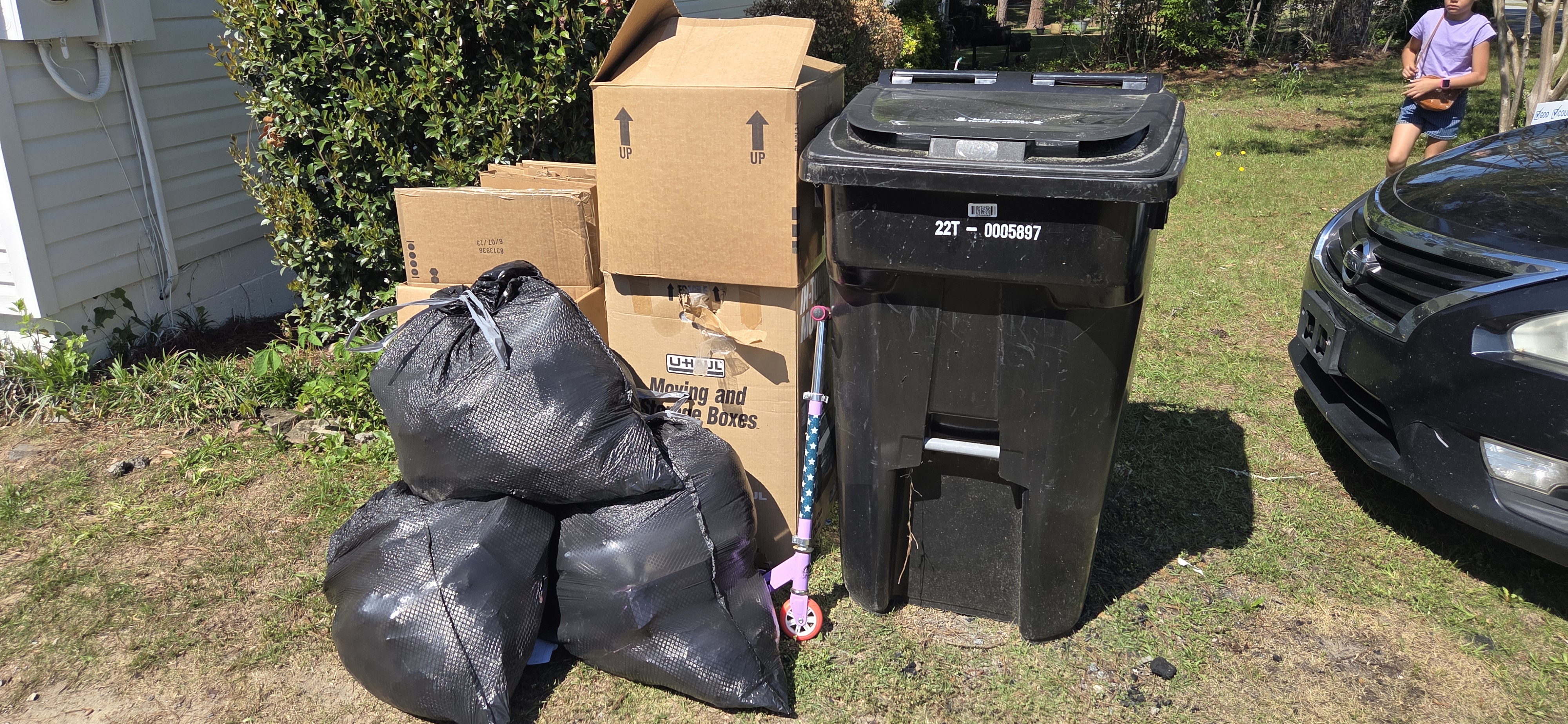 Curbside pickup — garbage bags, moving boxes, and trash can at curb in Columbus GA