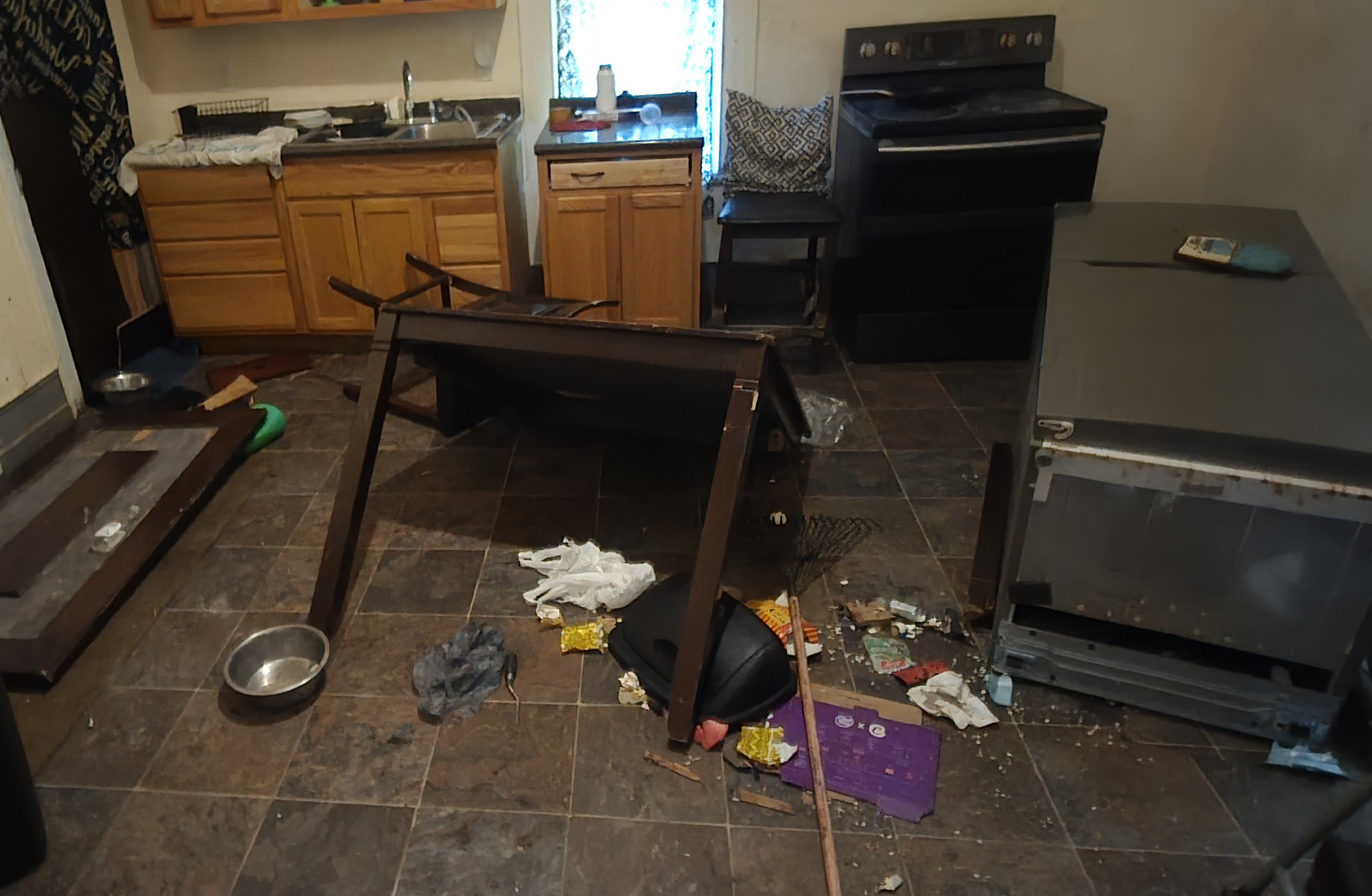 Trashed rental property kitchen before cleanout — broken furniture and debris on floor — Go Forward Haulers