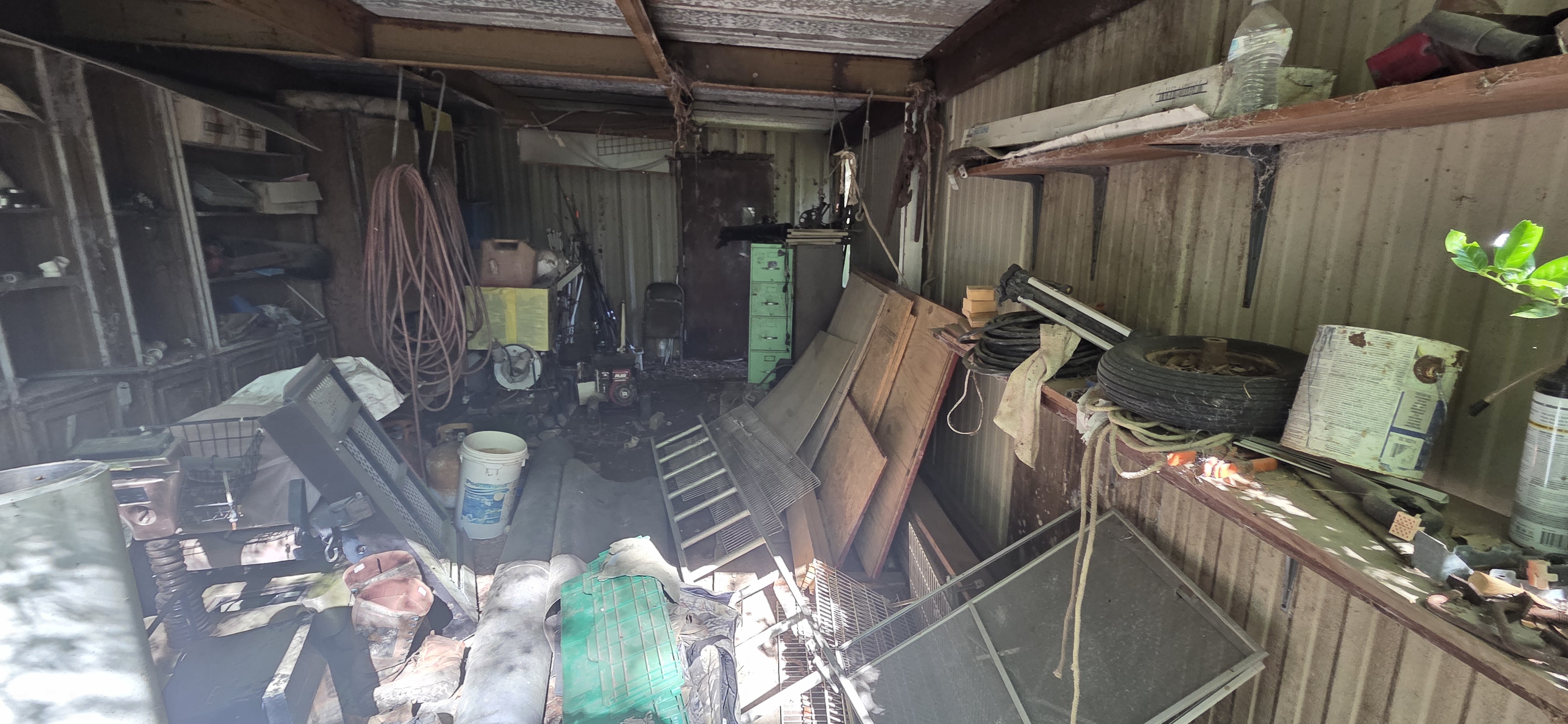 Interior of a completely packed shed before cleanout — tools, tires, furniture, and lumber — Go Forward Haulers